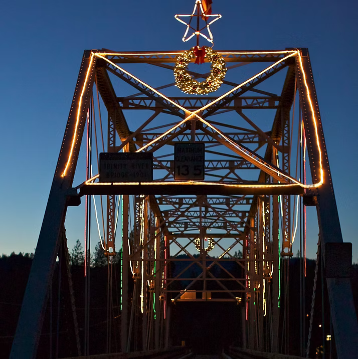 Lewiston Bridge lit with holiday lights, wreath, and star at dusk
